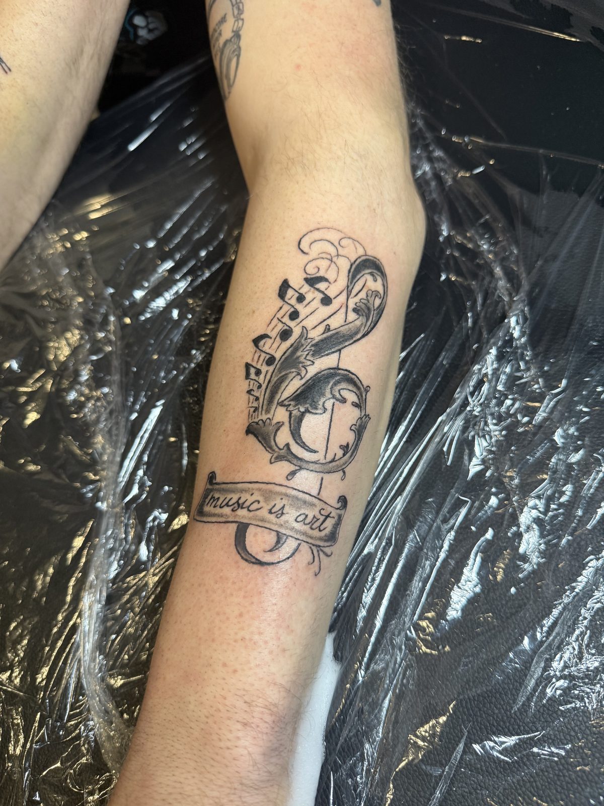 Lettering tatoeage: notenbalk met tekst, onderarm